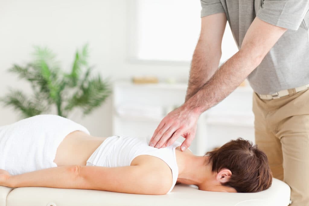 Chiropractor performing spinal adjustment on patient in therapeutic setting, emphasizing holistic healing and pain management for old injuries.