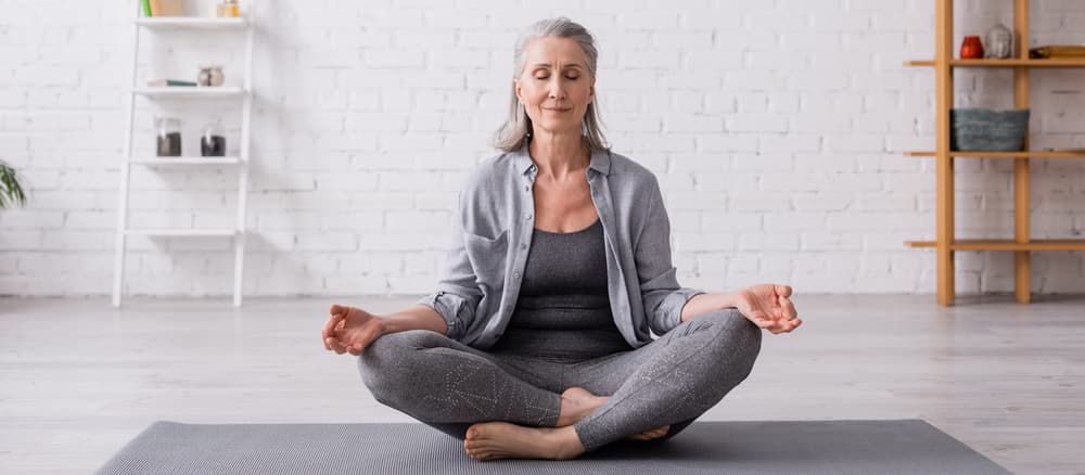 Older woman practicing yoga in a serene indoor setting, promoting flexibility and mindfulness, relevant to chiropractic care benefits.